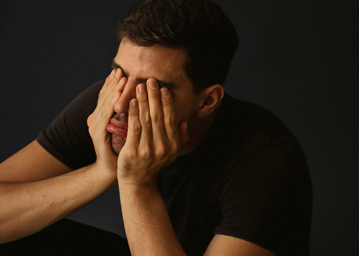 Stressed man with hands covering face, illustrating real-life insurance horror experiences.