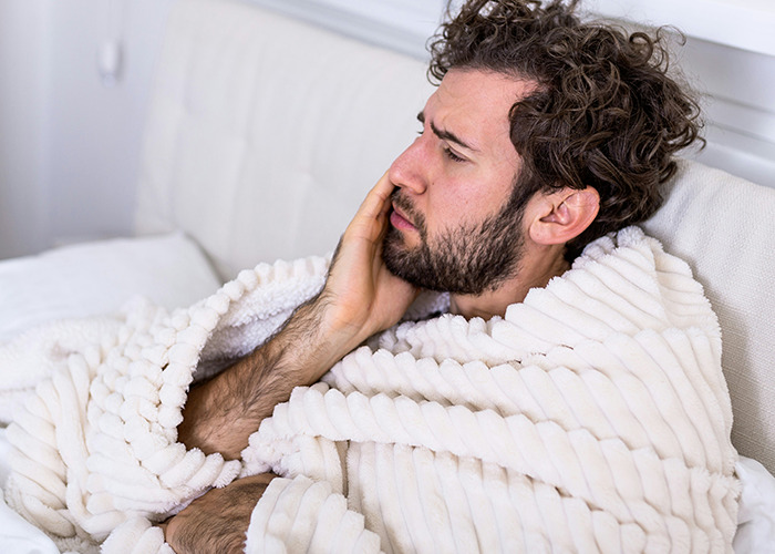 Man wrapped in a blanket looking concerned, possibly reflecting on real-life insurance issues.