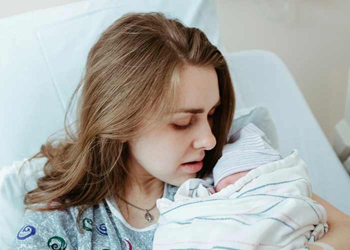 New mother holding her newborn in a hospital, reflecting on a surprising insurance story.