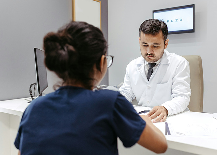 Doctor discusses insurance issues with a patient at a desk, highlighting real-life insurance challenges in healthcare settings.