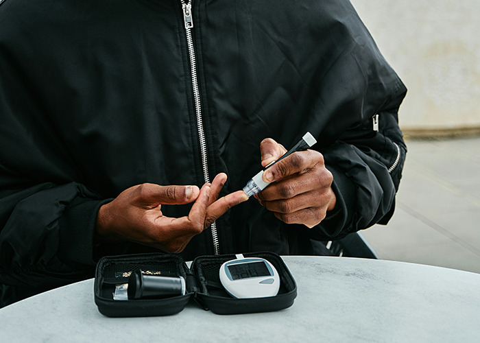 Person testing blood sugar with a glucometer, illustrating real-life insurance challenges.