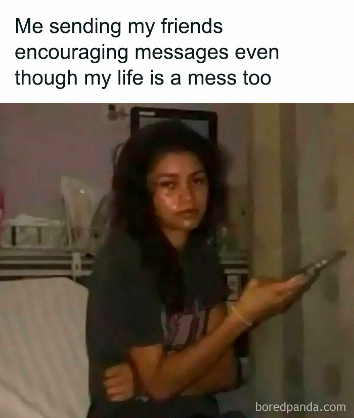 A person sitting on a bed, holding a phone, with a tired expression, representing introverted and anxious feelings.