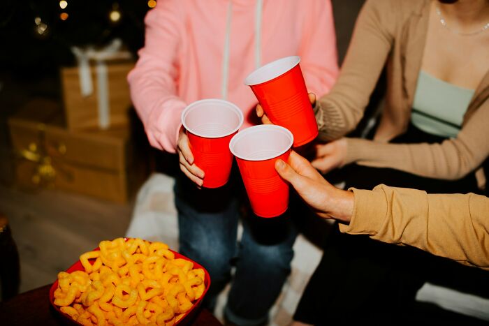Employees clinking red cups at a work Christmas party, with snacks in the foreground after a potluck gathering.
