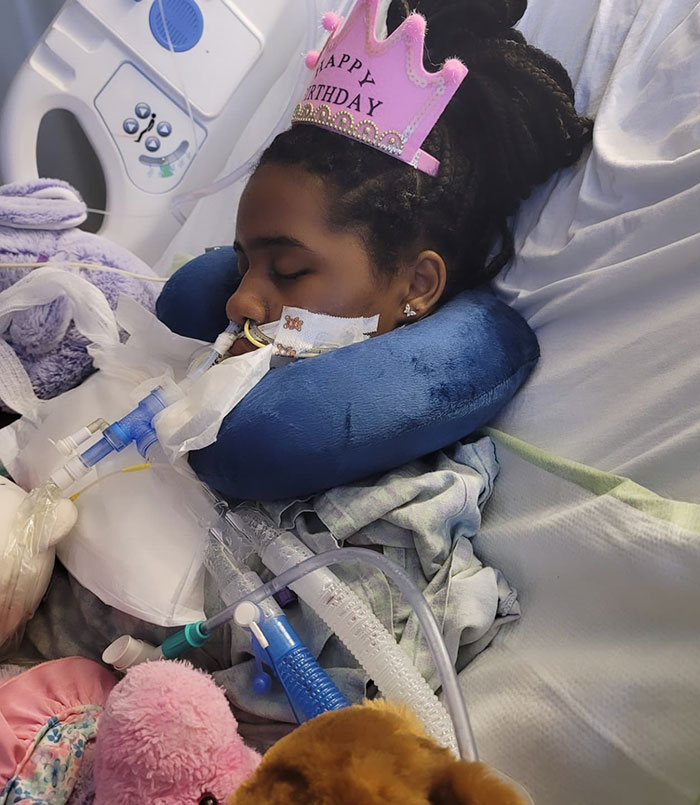 Kelaia Turner recovering in hospital bed with medical equipment, wearing a birthday crown. Kelaia Turner recovering in hospital bed with medical equipment, wearing a birthday crown.