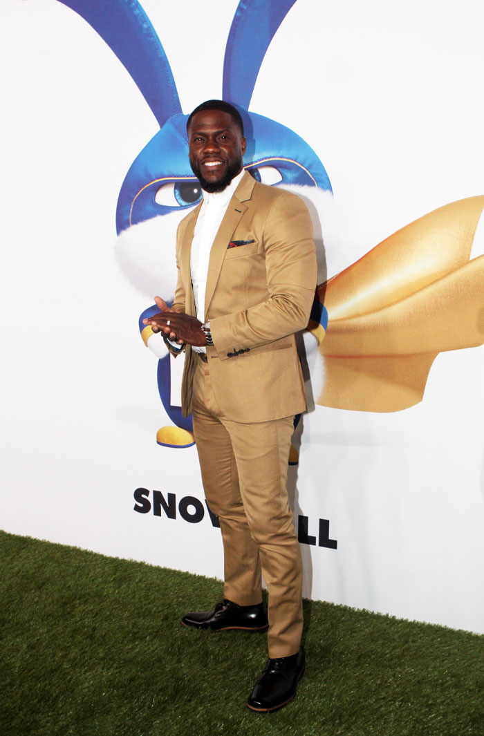 Kevin Hart poses in a tan suit at a promotional event for his character Snowball from "The Secret Life of Pets."