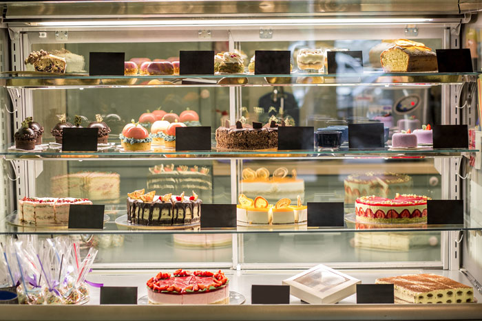 A bakery display case featuring a variety of colorful cakes and desserts, relevant to kids-revenge-sil.