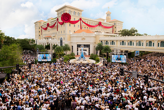 Large crowd gathered at a Scientology event outside a decorated building.