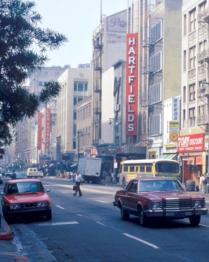 1970s West Coast street scene with vintage cars and storefronts, showcasing iconic era architecture and bustling urban life.