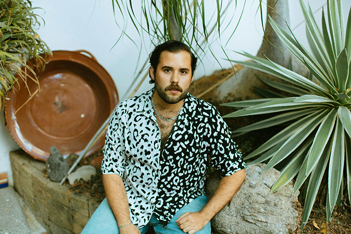 Man sitting outside in a garden, wearing a patterned shirt.