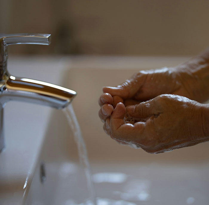 Hands under running water from a faucet, illustrating unattractive hygiene habits.