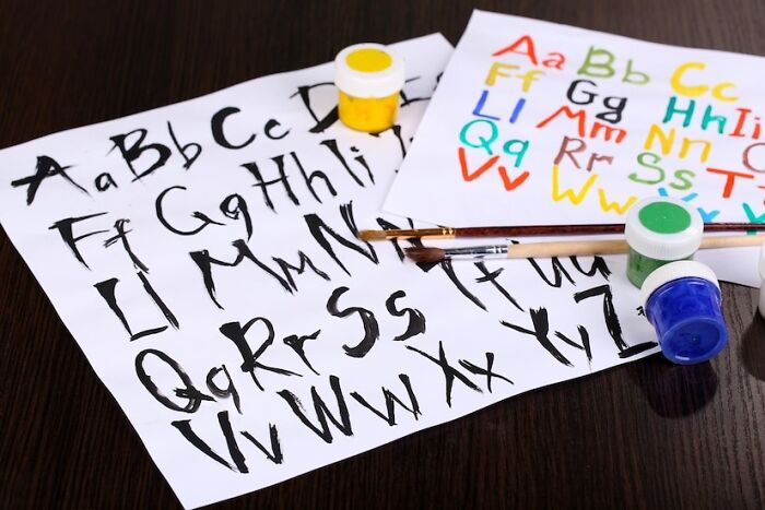 Left-handed struggles: messy handwriting on paper with paint jars and brushes.