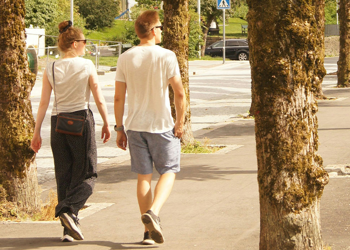 Two people walking outdoors, embracing a health hack by enjoying a 5-minute walk in a sunny park setting.