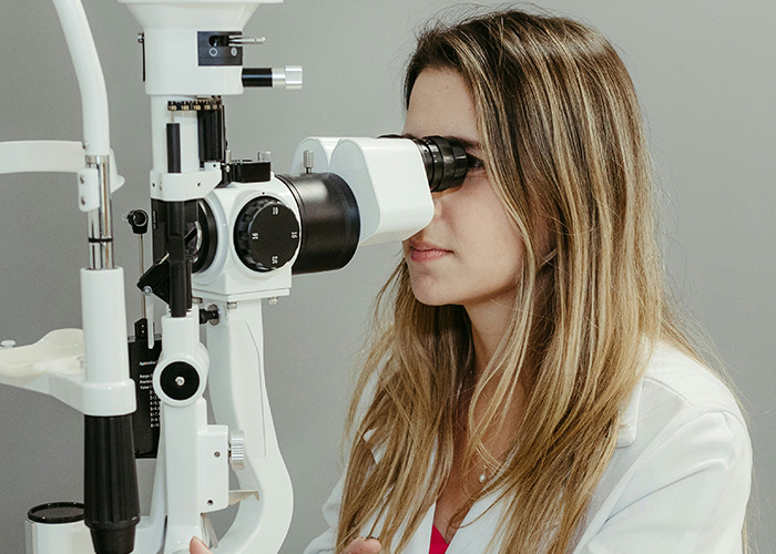 Woman checking her eyes with an optical device, highlighting health hacks.