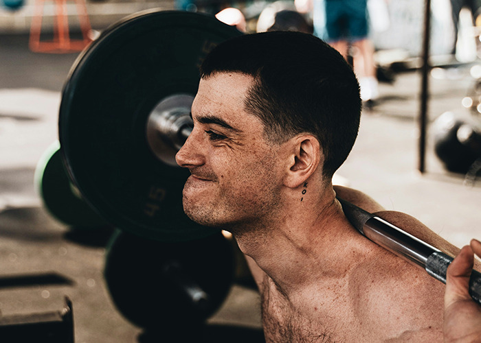 Man lifting weights in a gym, demonstrating a health hack with focused expression and determination.