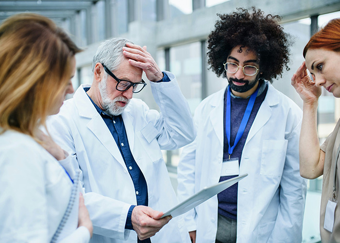 Doctors in discussion, examining a document in a health-related meeting, emphasizing health hacks.