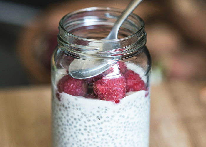 Chia pudding in a jar topped with fresh raspberries, showcasing a popular health hack for nutritious eating.