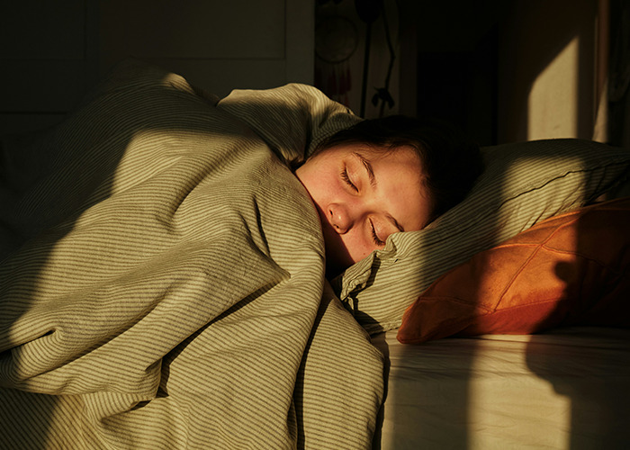 Person sleeping peacefully under a blanket, illustrating a health hack for better rest.
