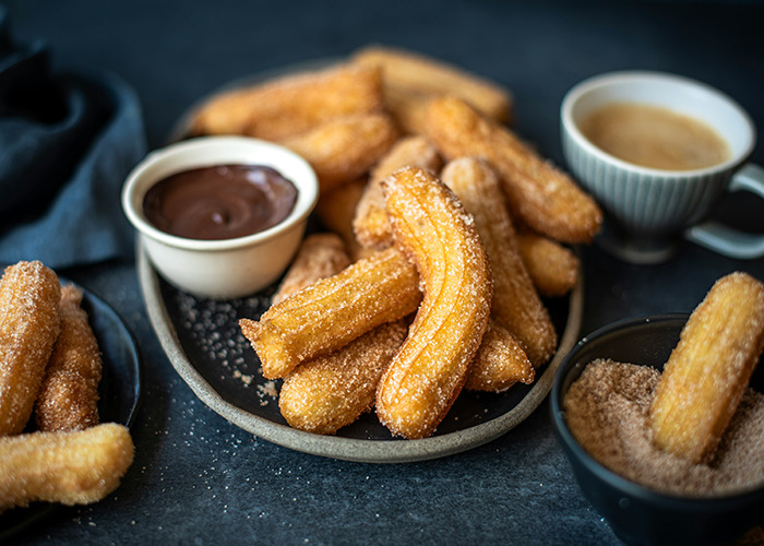Plate of churros with chocolate sauce and coffee, highlighting a simple health hack enjoying a sweet treat in moderation.