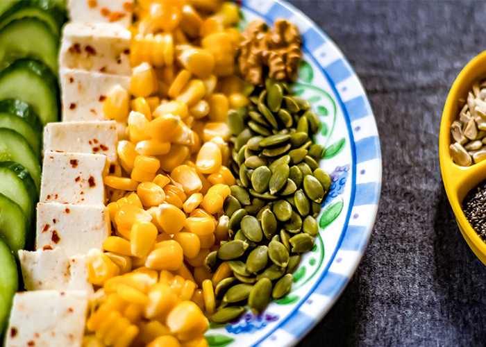 Healthy food platter with cucumbers, tofu, corn, pumpkin seeds, walnuts, and seeds, highlighting health hacks benefits.