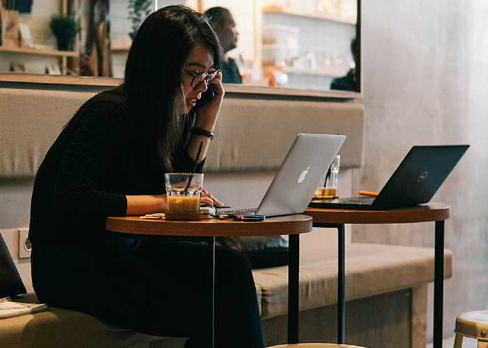 Person in a cafe working on laptops, emphasizing health hacks and taking a break for a short walk.