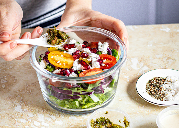 Healthy salad preparation with fresh vegetables, feta, and pomegranate seeds, highlighting a simple health hack.