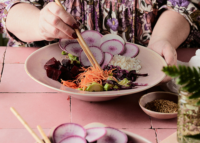 Person preparing a healthy vegetable salad with radishes, beets, carrots, and cabbage, showcasing simple health hacks.