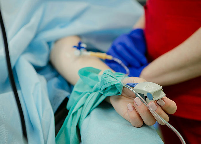 Person receiving medical treatment, highlighting a life-changing moment with blue gown and IV in a hospital setting.