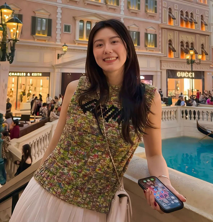 Former Chinese athlete smiling in a stylish outfit, standing by a canal in a shopping mall. Gucci store visible in background. Former Chinese athlete smiling in a stylish outfit, standing by a canal in a shopping mall. Gucci store visible in background.