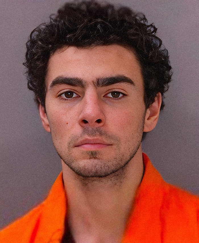 Luigi Mangione mugshot, Luigi in an orange shirt looking directly at the camera.