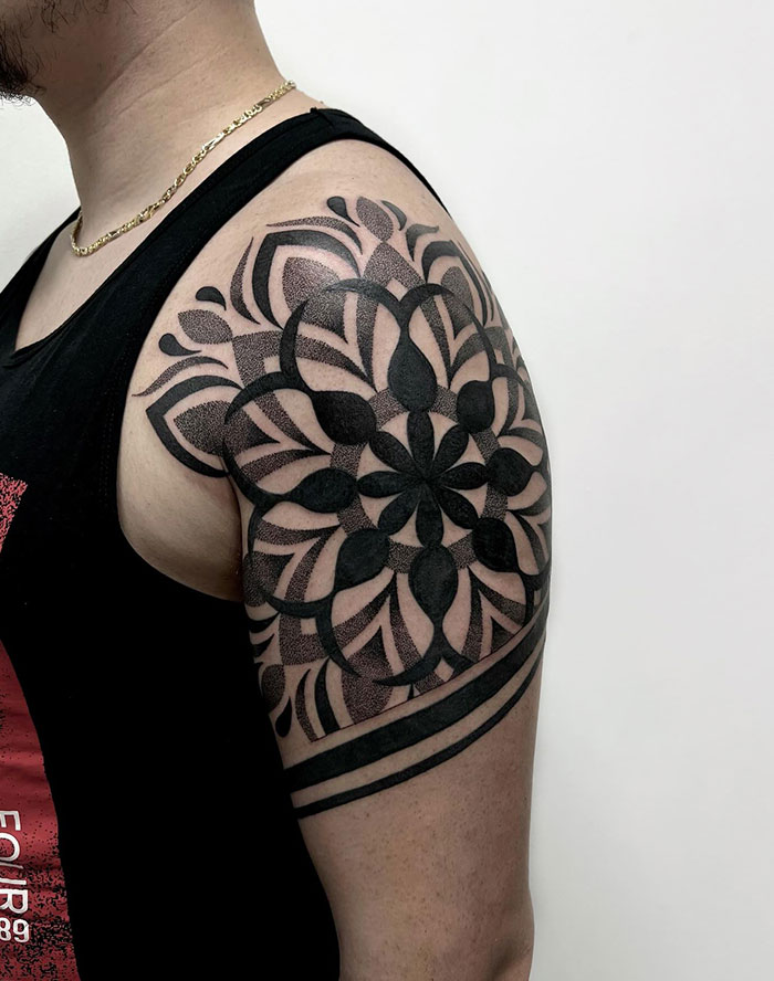 Mandala tattoo design on a person's upper arm, showcasing intricate patterns in black ink, ideal placement idea.
