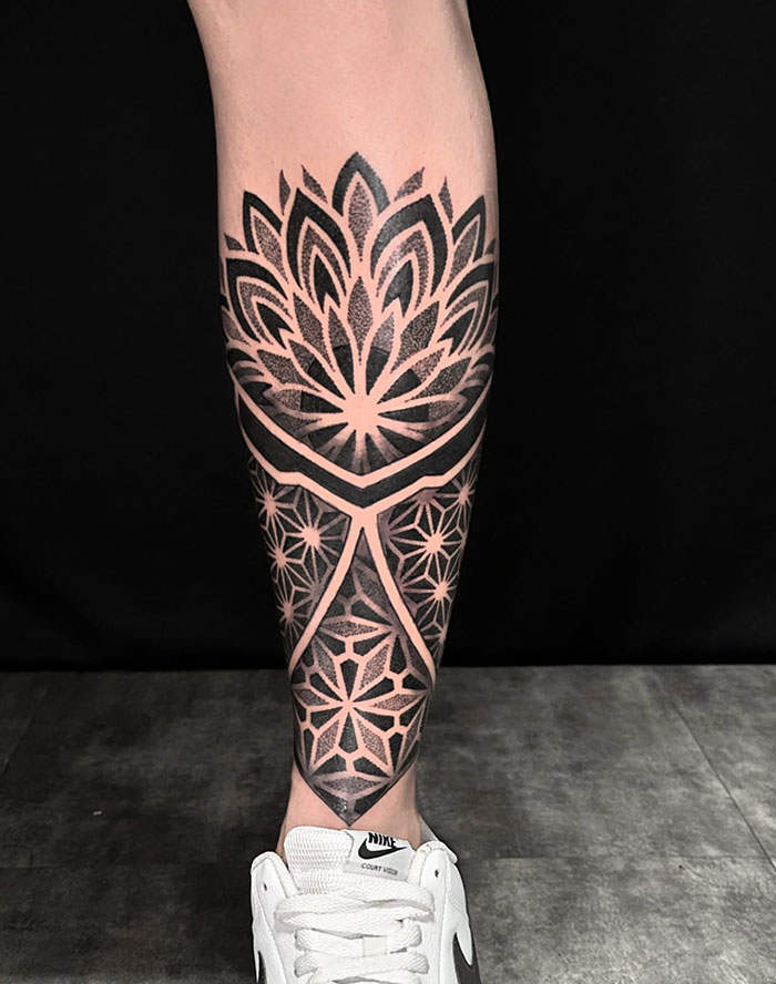 Intricate mandala tattoo design on a leg, showcasing detailed patterns and placement above a white sneaker.