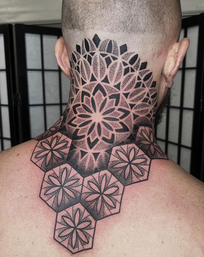 Intricate mandala tattoo on the back of a person's neck, showcasing geometric and floral patterns.