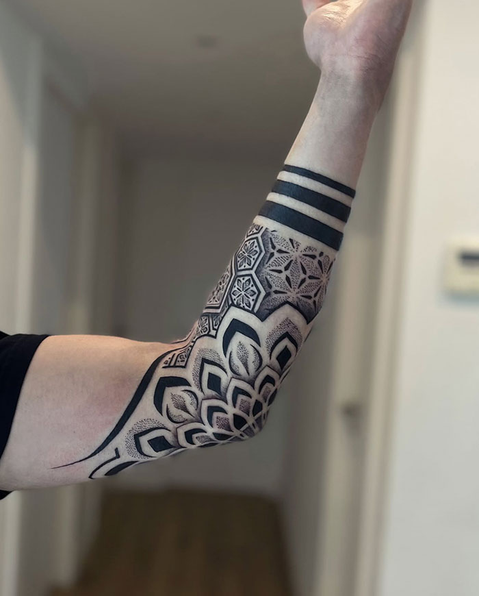 Forearm with intricate mandala tattoo design, featuring geometric patterns and bold lines.