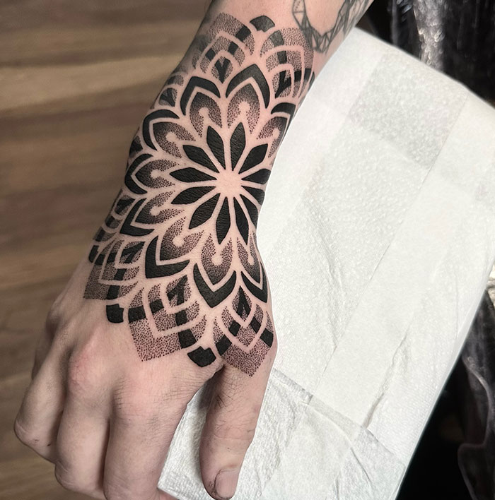 Mandala tattoo design on a hand, showcasing intricate black geometric patterns for meaningful body art.