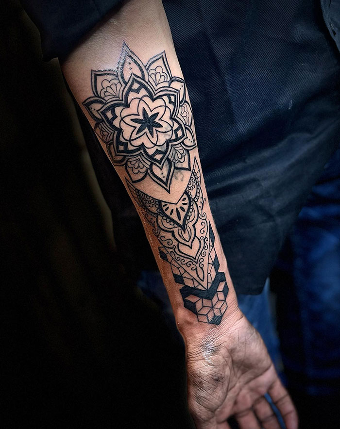 Intricate mandala tattoo on a forearm, showcasing detailed patterns and geometric shapes.