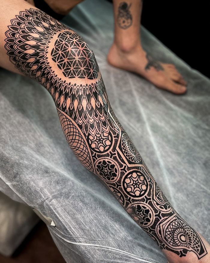 Intricate mandala tattoo on a person's leg, showcasing detailed geometric patterns and design ideas.