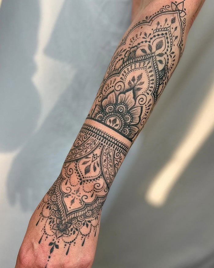 Intricate mandala tattoo design on forearm, featuring detailed patterns and artistic shading.