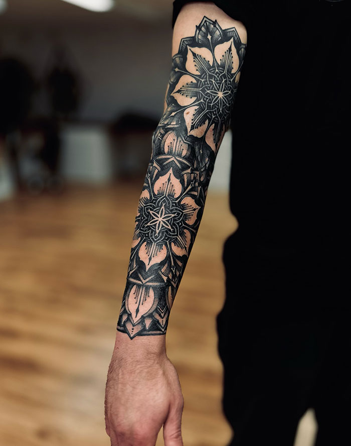 Intricate mandala tattoo design on a forearm, highlighting geometric patterns and shading techniques.
