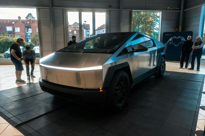Futuristic car exhibit with people observing, capturing 2024 trends.