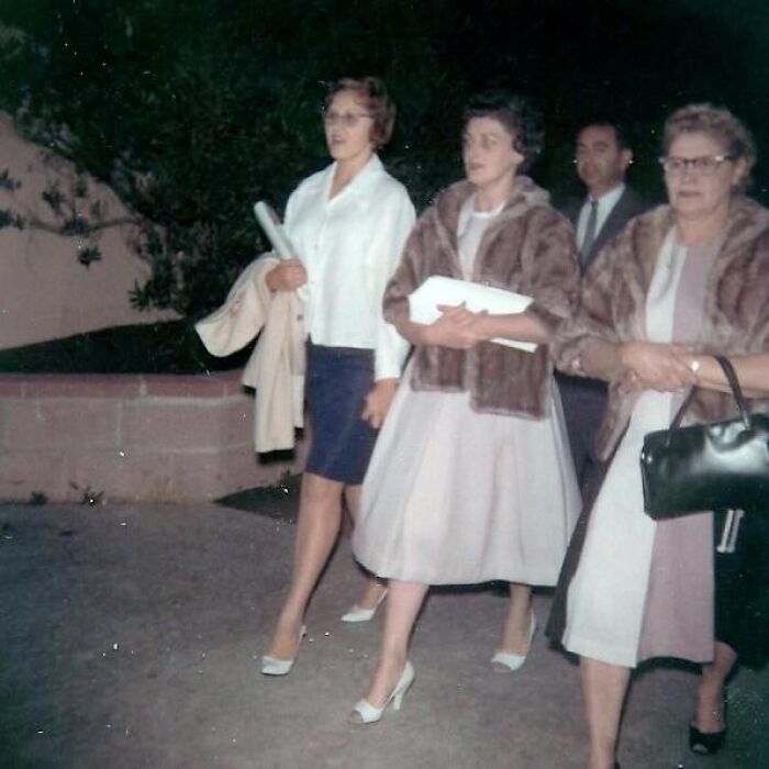 Women in vintage 60s fashion, featuring fur coats and elegant dresses, walking with their purses and documents in hand.