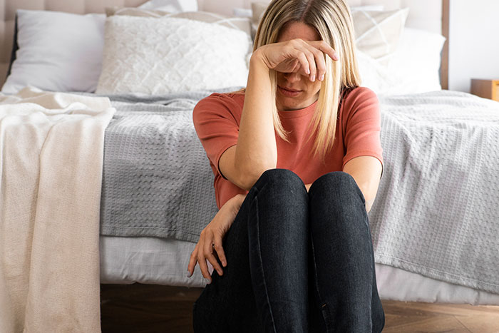 New mom sitting emotionally upset on the floor, hand covering her face. New mom sitting emotionally upset on the floor, hand covering her face.