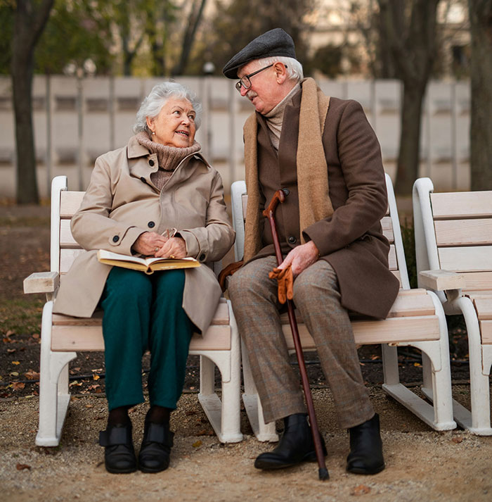Elderly couple on a park bench, smiling and talking, challenging stereotypes about being "born gifted."