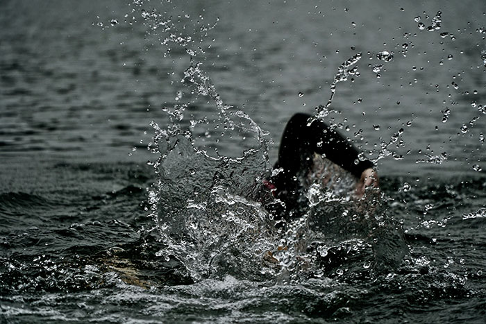 Person swimming in rough water at the beach, causing a splash.