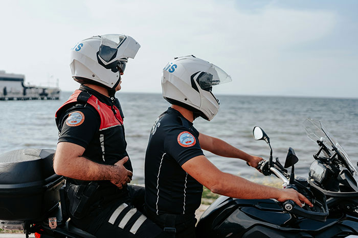 Police officers on a motorcycle by the beach.