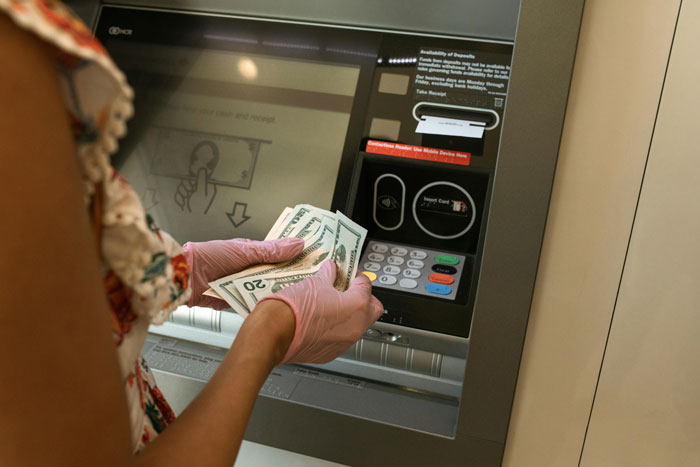 Woman withdrawing cash from ATM for a family emergency, holding dollar bills. Woman withdrawing cash from ATM for a family emergency, holding dollar bills.