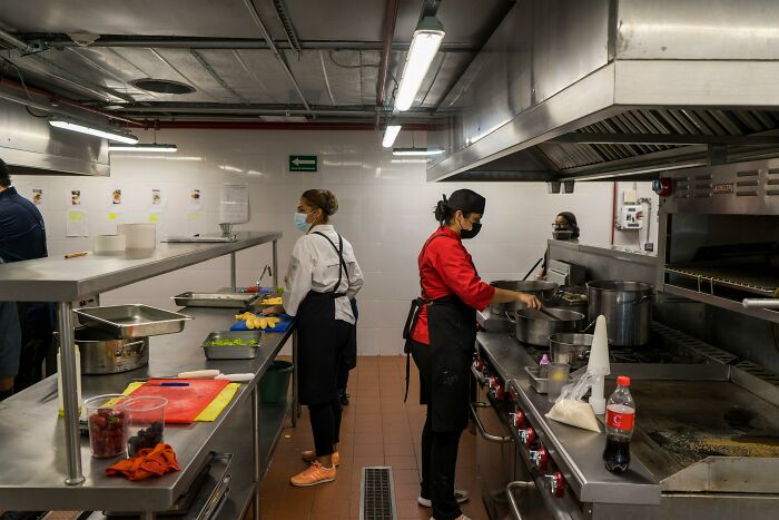 Chefs in a commercial kitchen preparing meals, highlighting culinary practices that may be seen as outdated in the future.