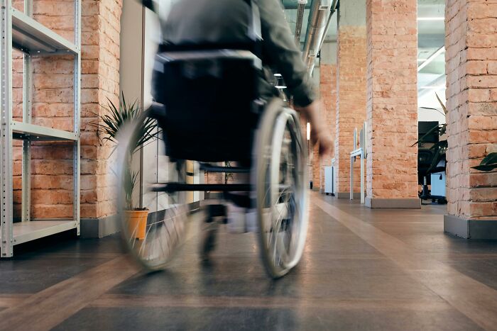 A person in a wheelchair moves through a modern hallway, highlighting accessibility in contemporary design.