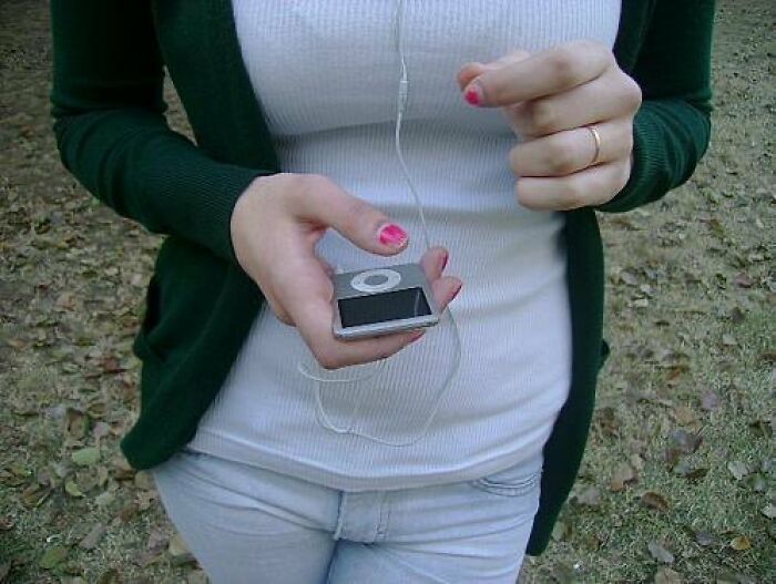 Person holding an old mp3 player with earphones, evoking an old-internet-feel.