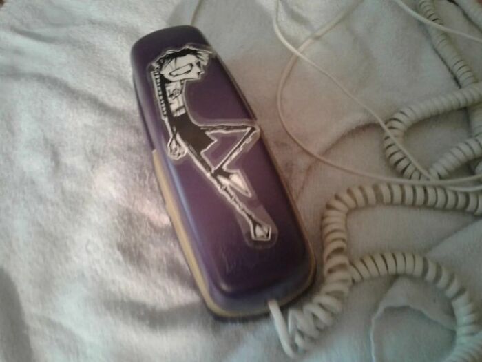 Vintage purple landline phone with a cartoon sticker, capturing old-internet-feel aesthetics.