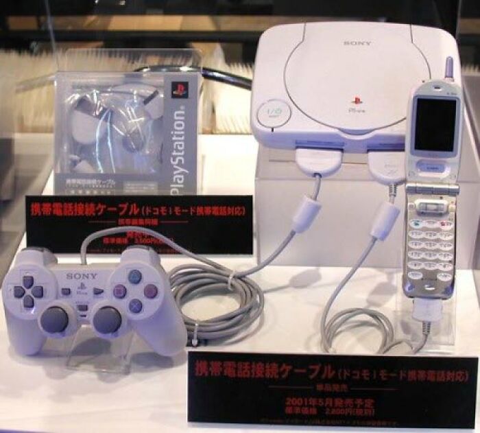 Old-Internet-Feel-Pics: Vintage Sony gaming console connected to a flip phone with controller displayed.